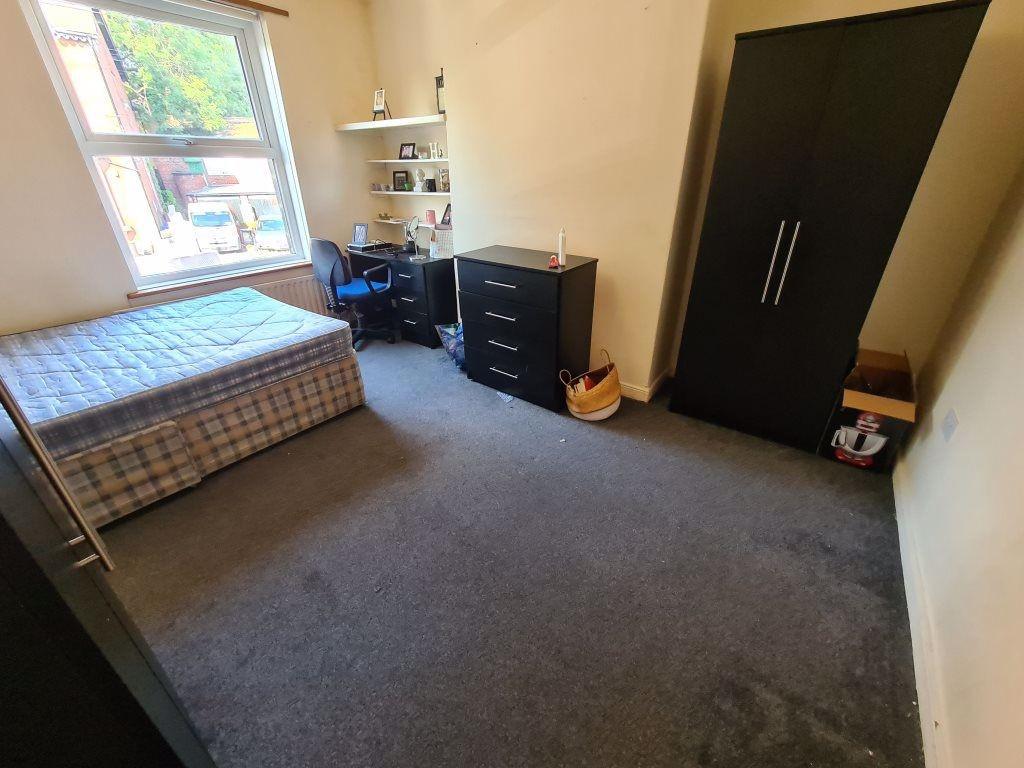 A modest student bedroom featuring a single bed...