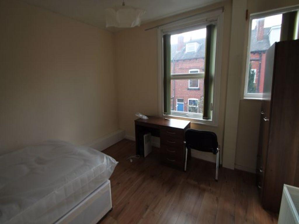 A cozy, well-lit single bedroom featuring a bed...