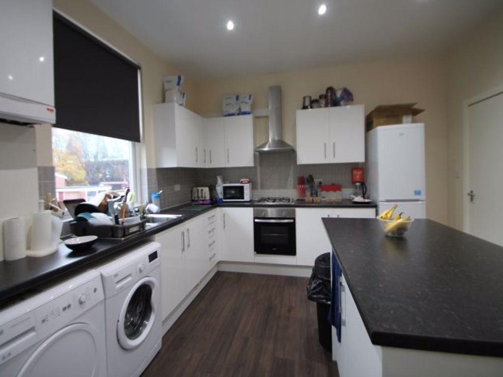 A modern kitchen featuring white cabinetry with...