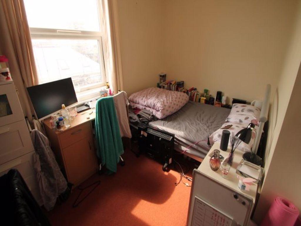 A cozy single bedroom featuring a large window ...