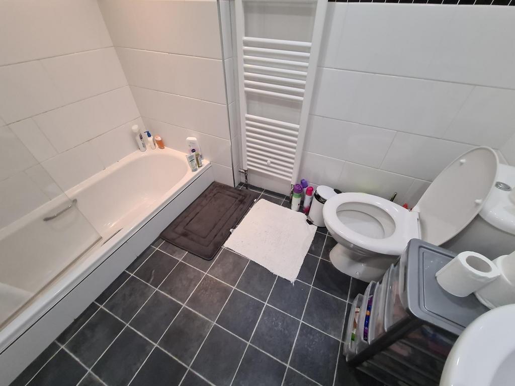 Clean, modern bathroom with a white bath, tiled...