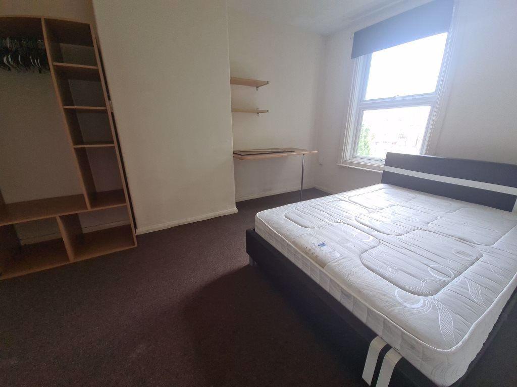A bright double bedroom featuring a large windo...