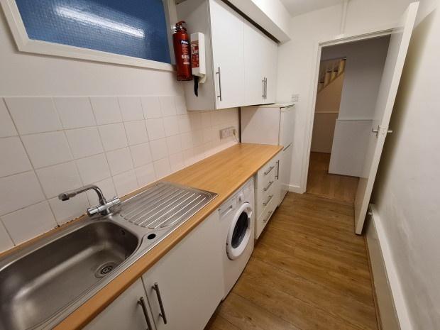 Long galley-style kitchen with wooden counterto...