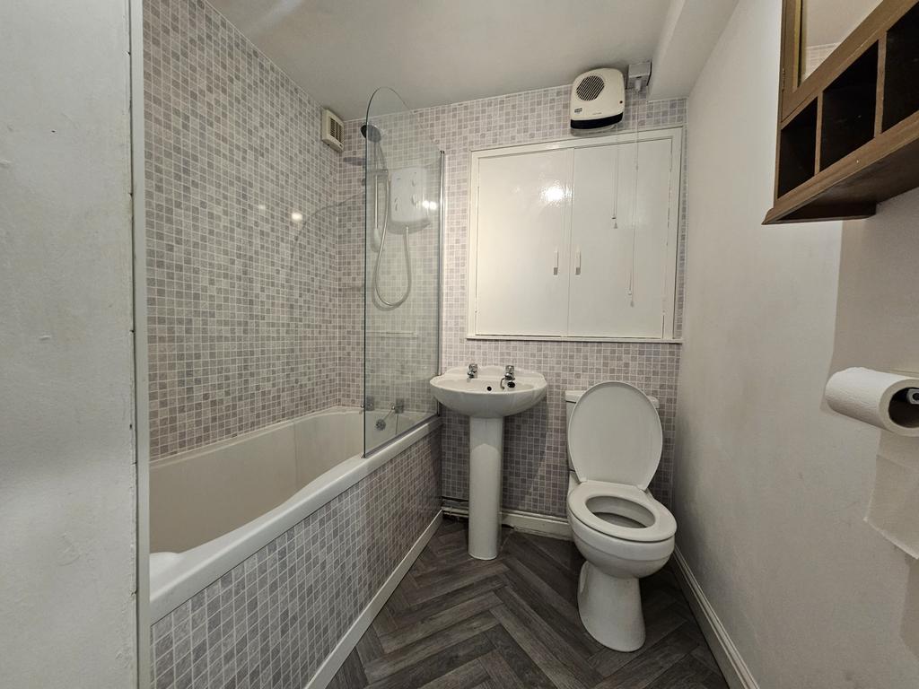 A modern bathroom featuring a bathtub with a gl...