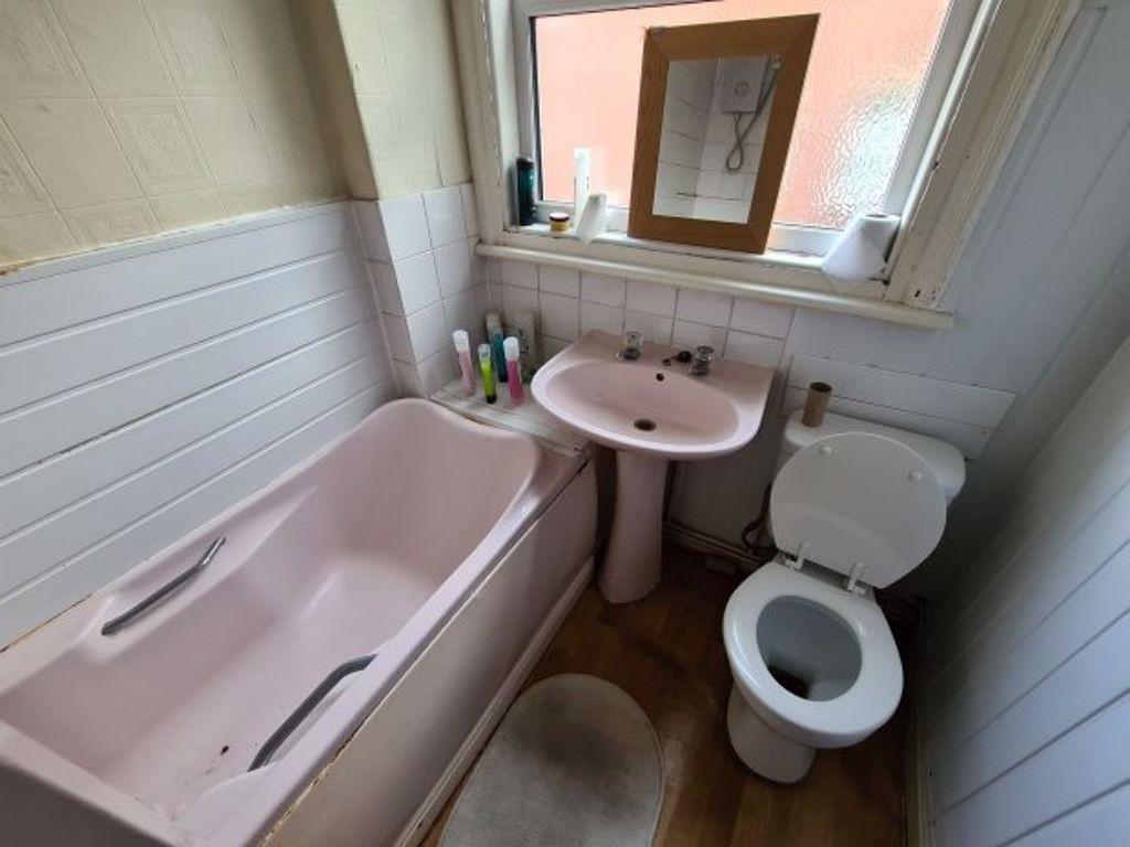 A cozy bathroom featuring a pastel pink bathtub...