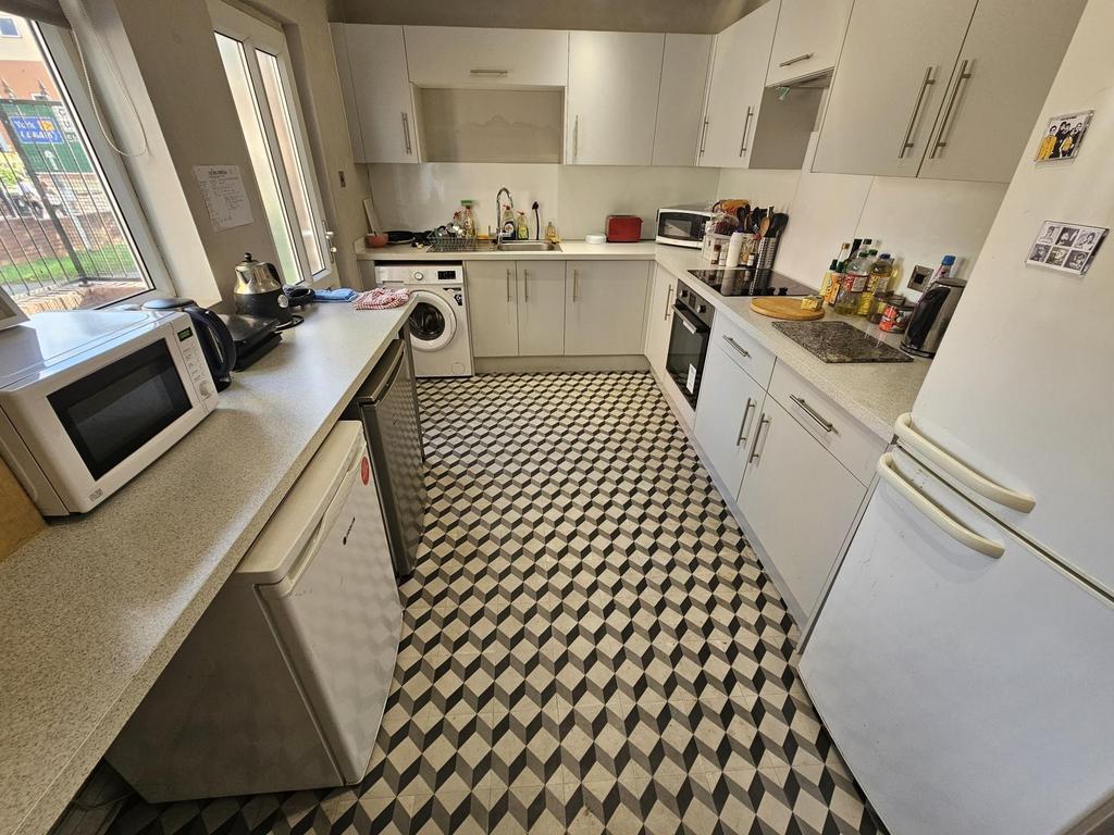 Bright, modern galley kitchen with white cabine...