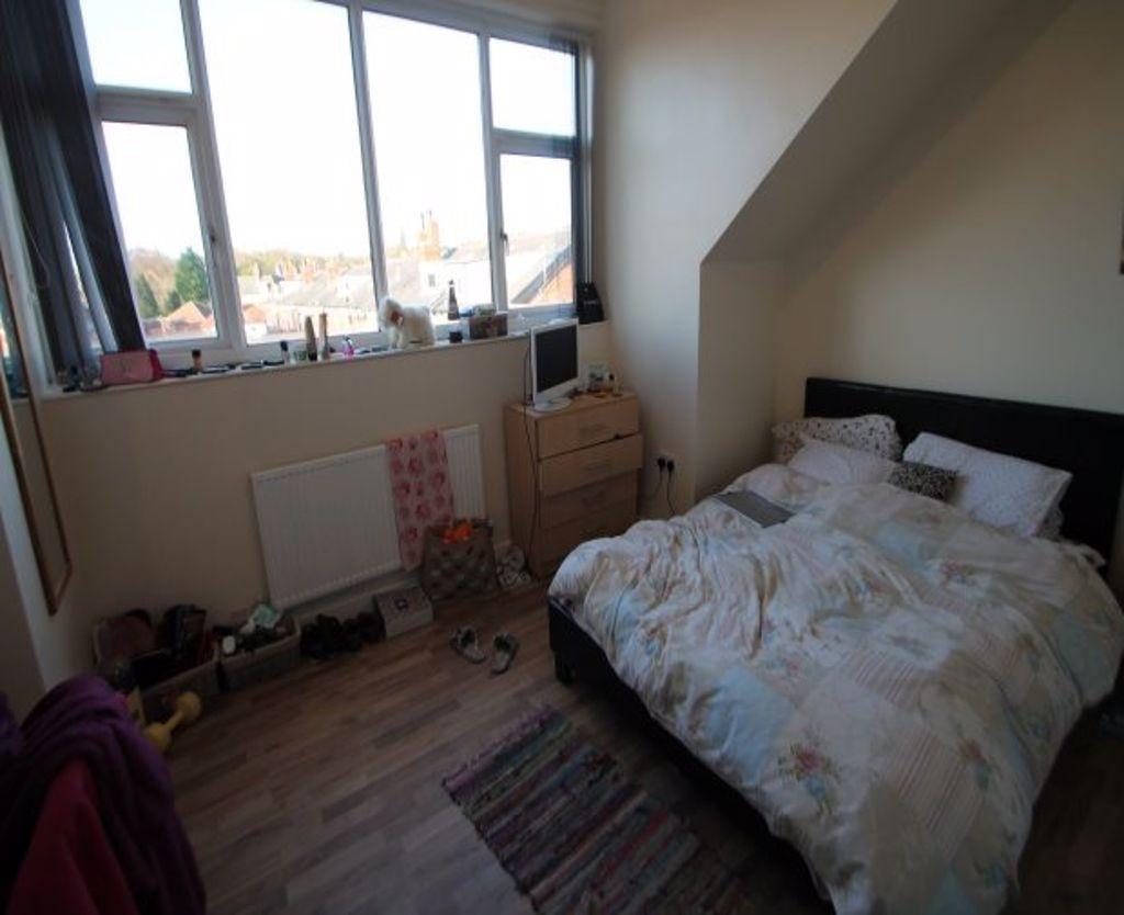 A cozy double bedroom with a large window letti...