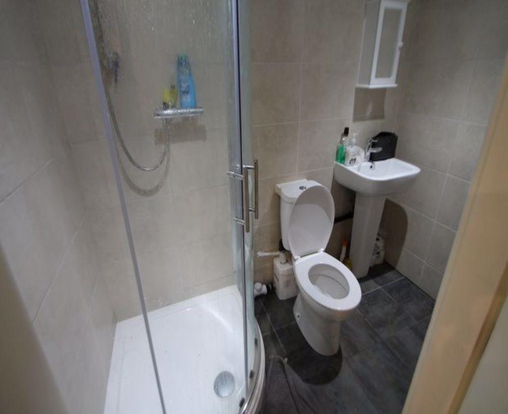 A modern bathroom featuring a curved glass show...