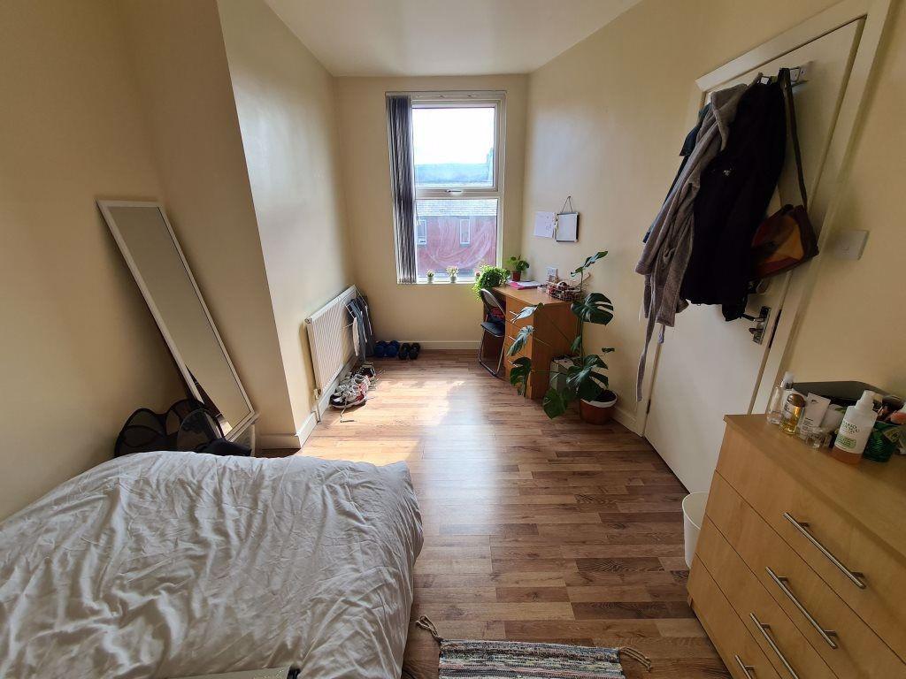 A cozy single bedroom featuring a large window ...