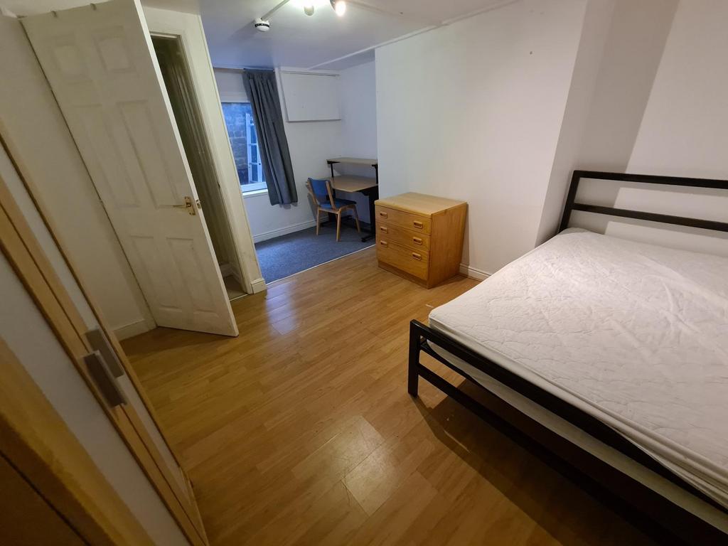 A tidy double bedroom featuring a bed, wooden f...