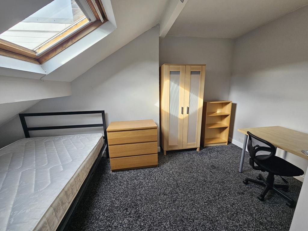 A well-lit single bedroom featuring a bed, a wo...