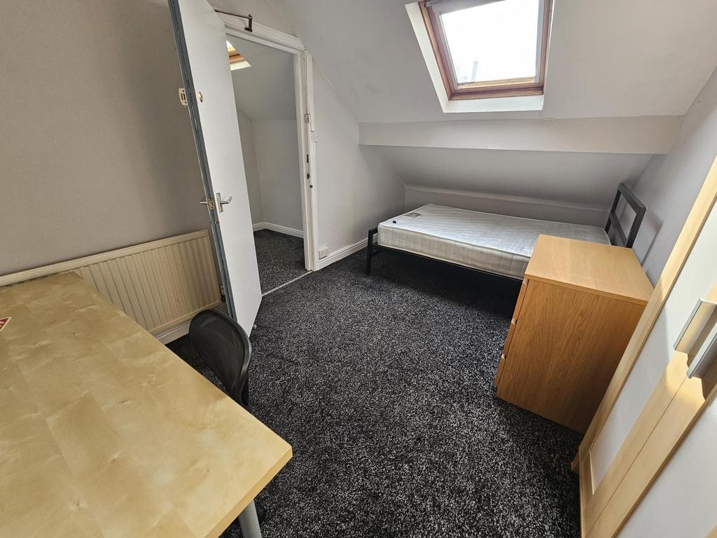A compact single bedroom featuring a simple bed...