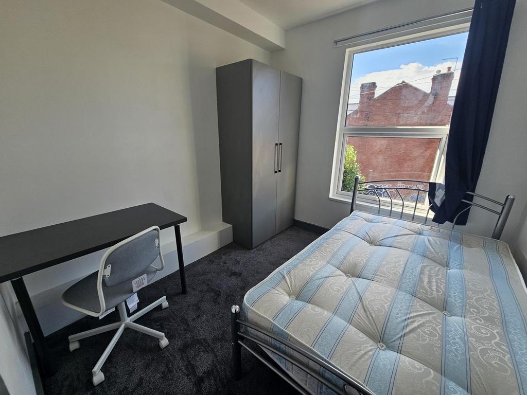 A neat and well-lit single bedroom featuring a ...