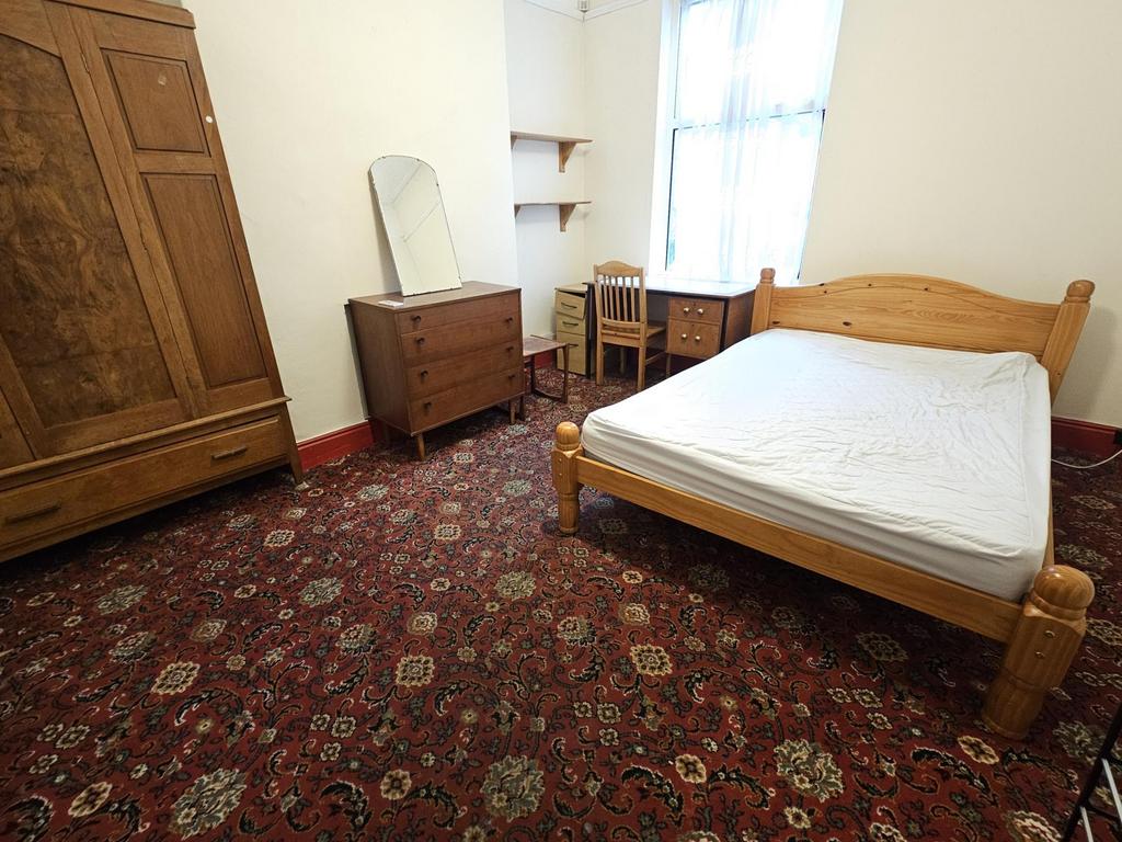 A cozy single bedroom featuring a wooden bed fr...