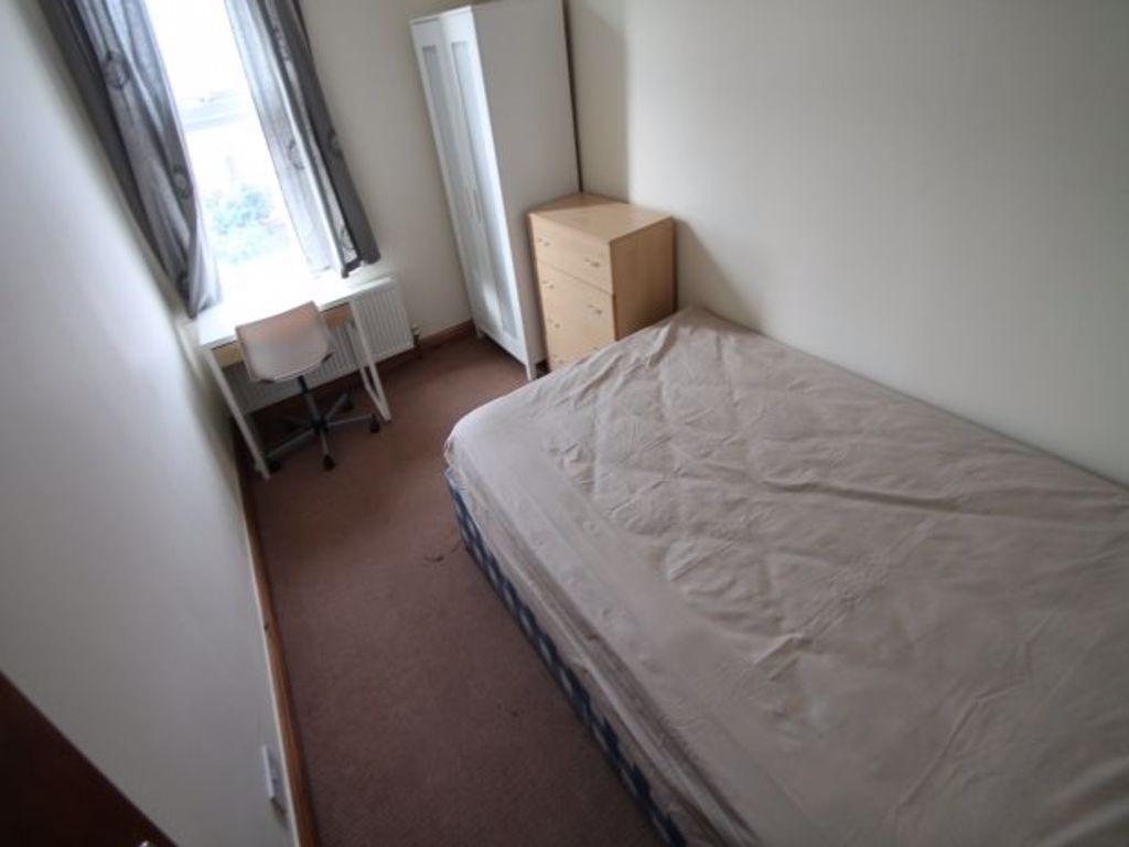A tidy and well-lit small bedroom with a single...