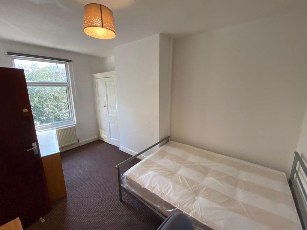 A simple, well-lit bedroom featuring a single b...