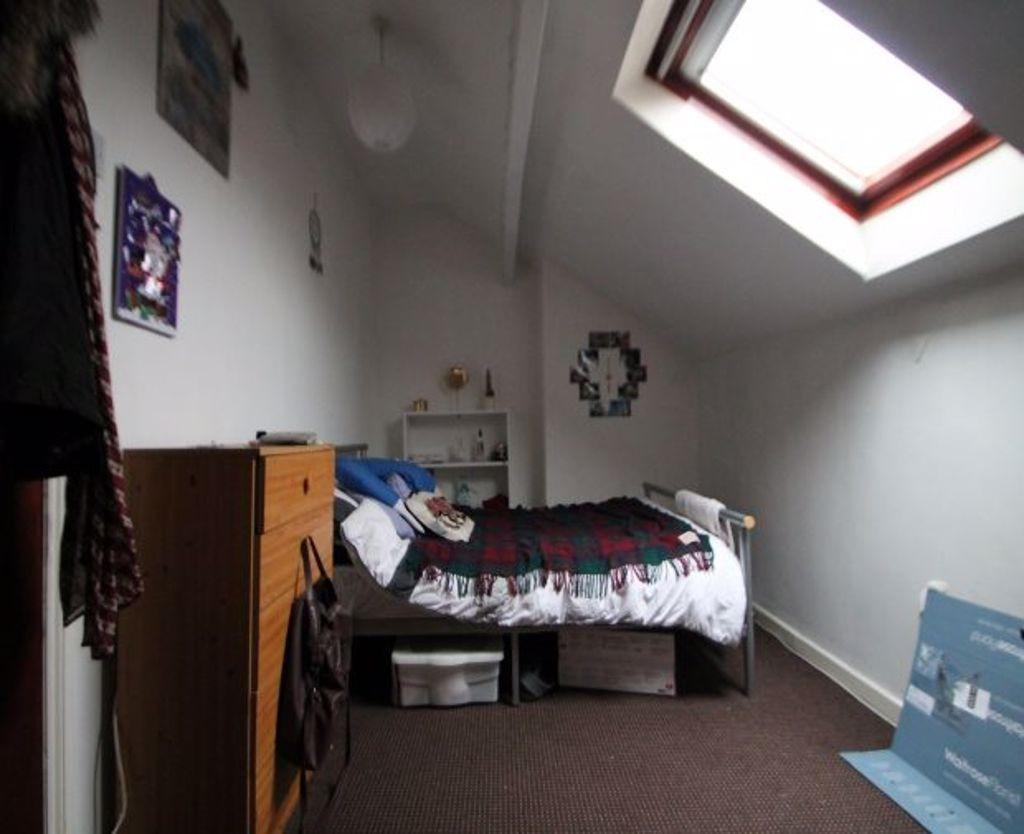 A cozy single bedroom featuring a skylight wind...