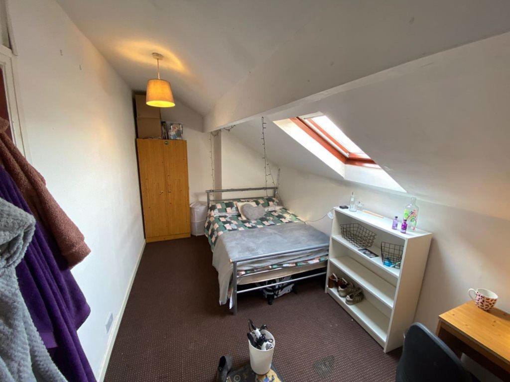 A cozy attic bedroom featuring a single bed ben...
