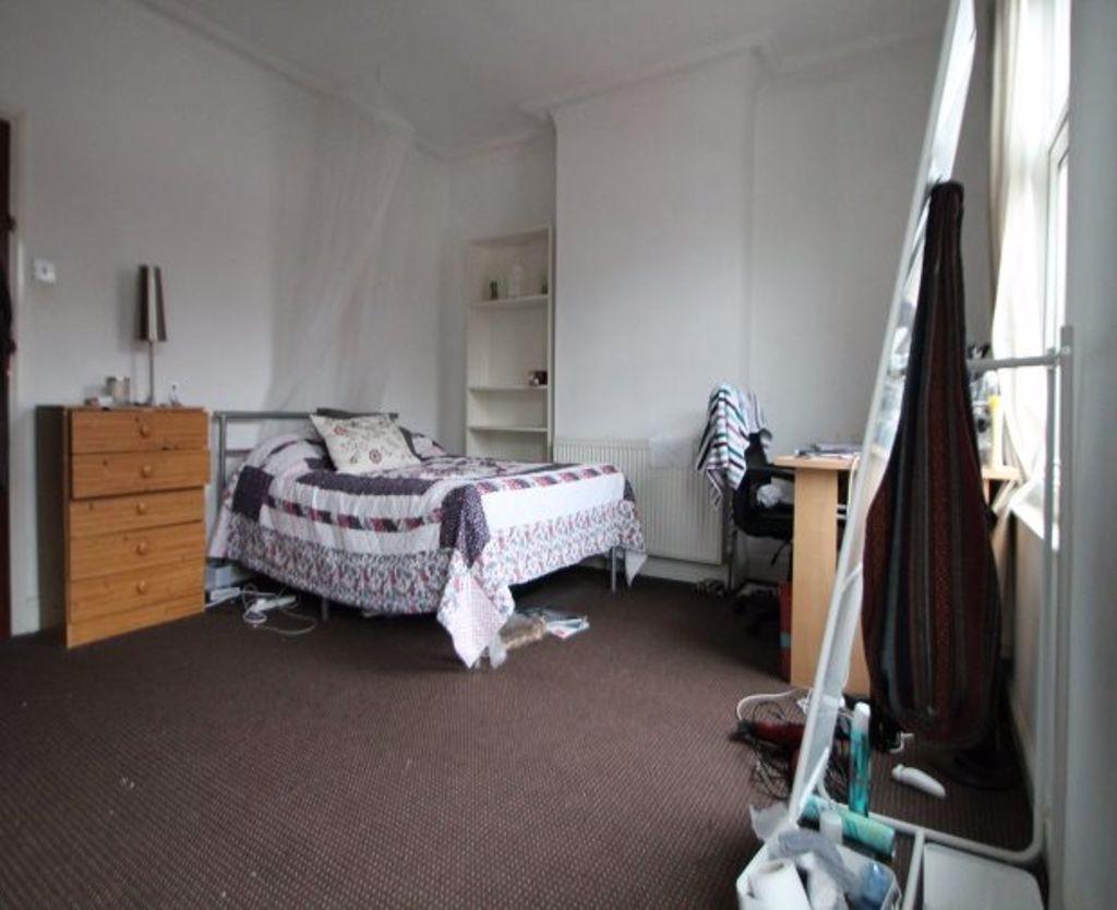 A simple and cozy single bedroom featuring a ti...