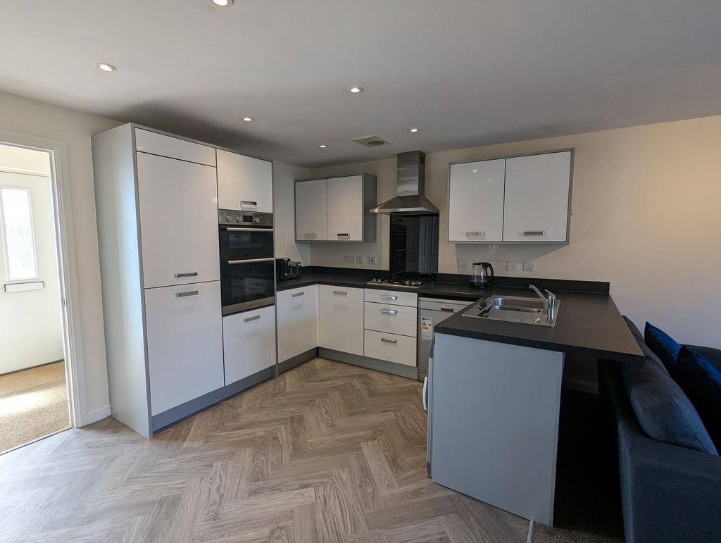 Modern kitchen featuring sleek white cabinets a...