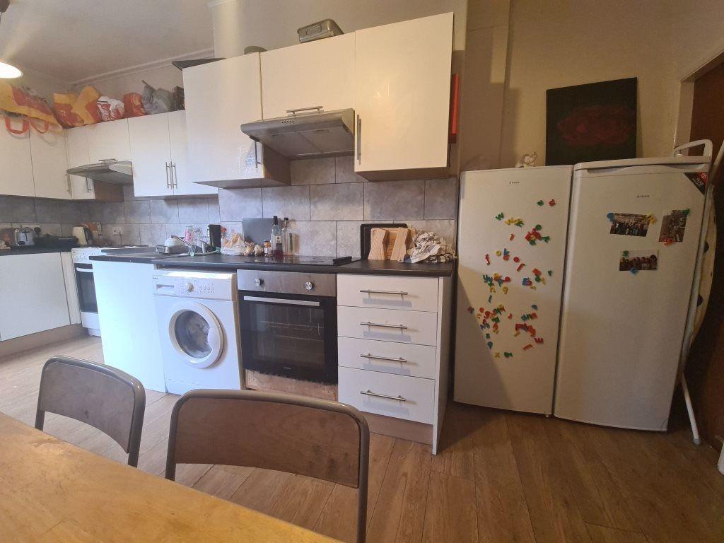 A modern kitchen with white cabinetry and woode...