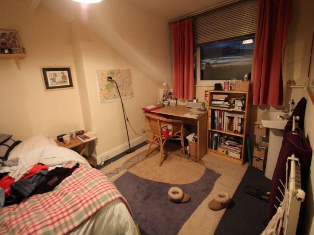 A cozy and well-used single bedroom featuring a...