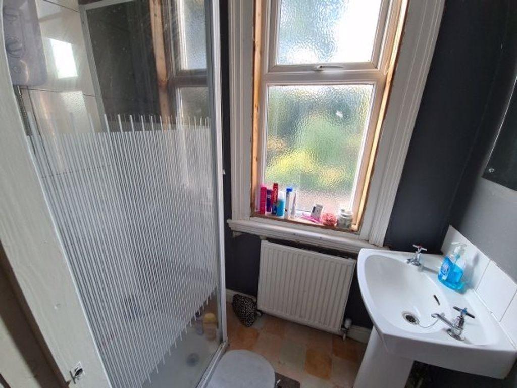A compact bathroom featuring a glass-enclosed s...