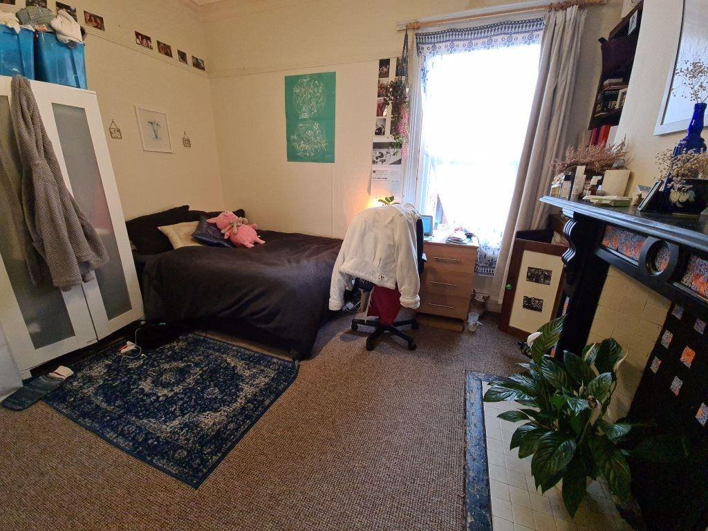 A cozy bedroom featuring a bed, desk, and a win...