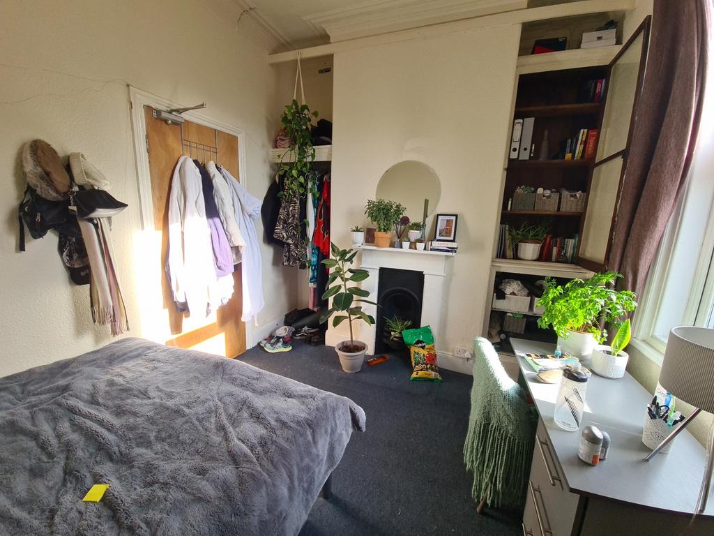 A well-lit bedroom featuring a large bed, ample...