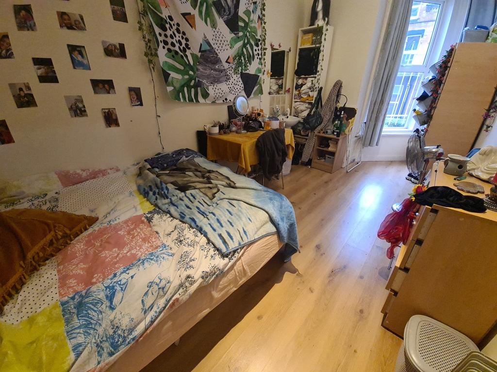 A cozy single bedroom featuring a bright wooden...