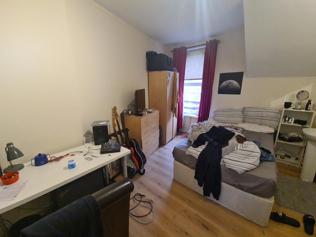 A cozy bedroom featuring a single bed, a study ...