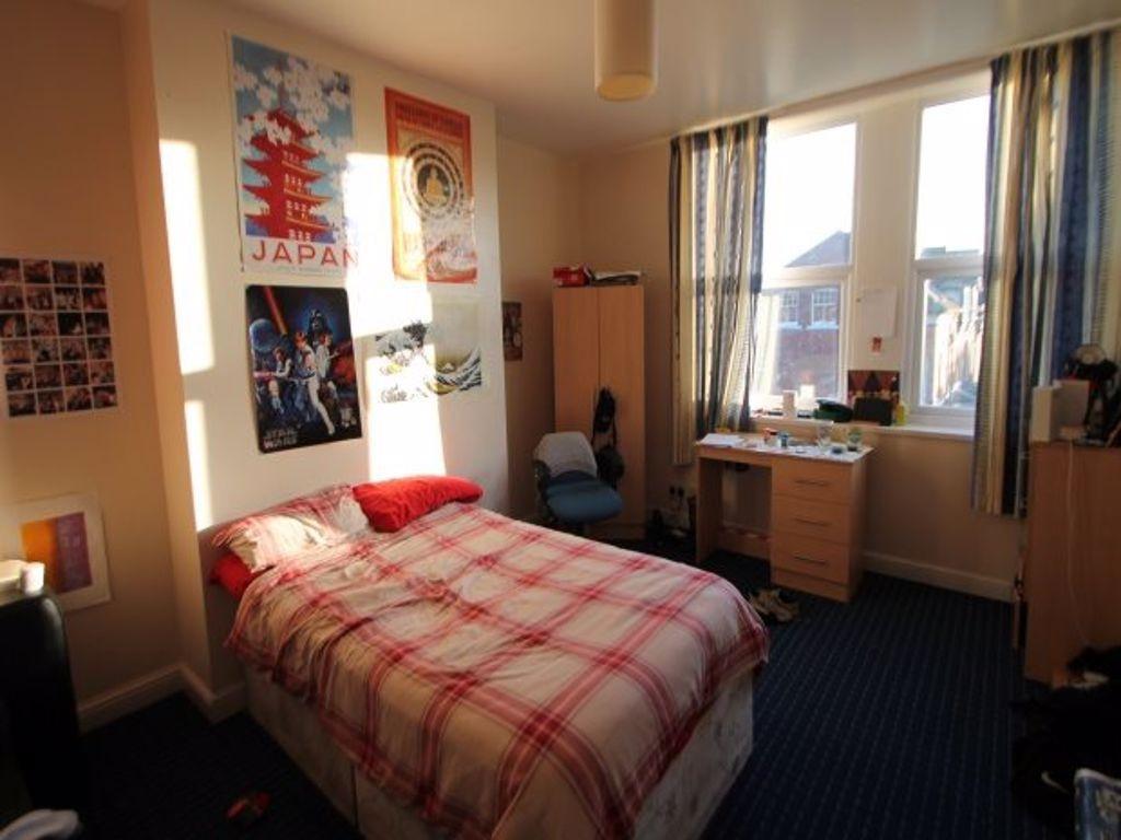 A bright, cozy single bedroom featuring a comfo...