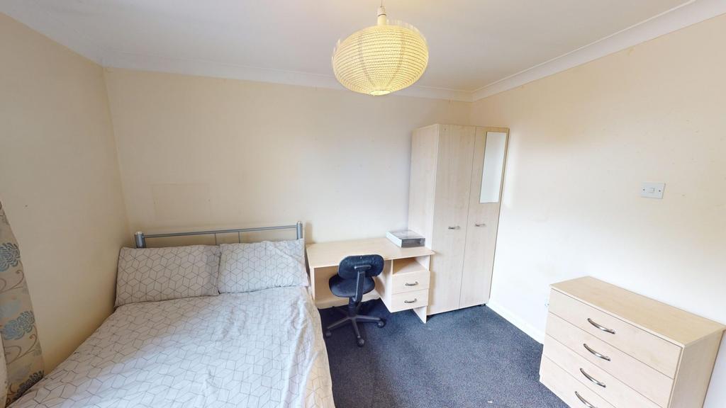 A cozy and tidy double bedroom with a desk and ...