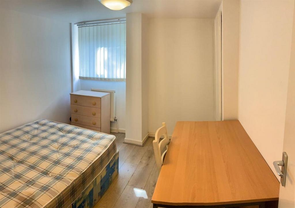 A neat and tidy single bedroom featuring a comf...