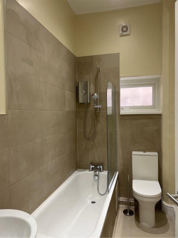 A modern bathroom featuring a clean, white bath...