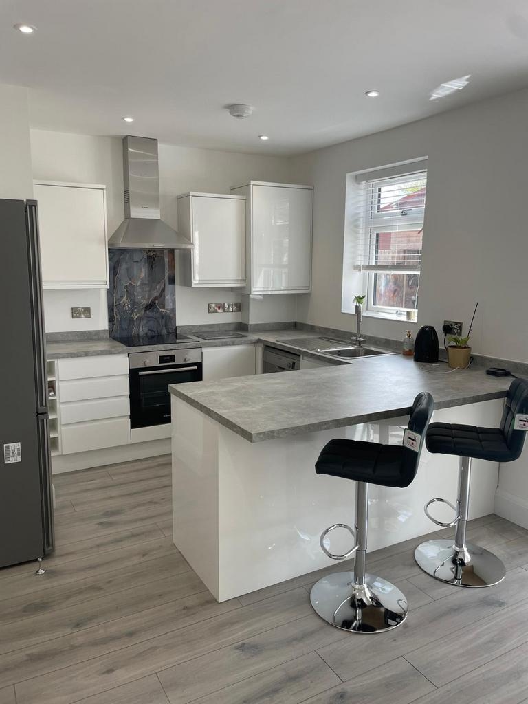A modern kitchen featuring sleek white cabinetr...