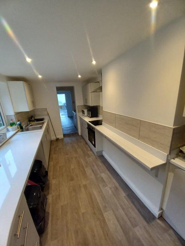 Modern galley kitchen with sleek white countert...