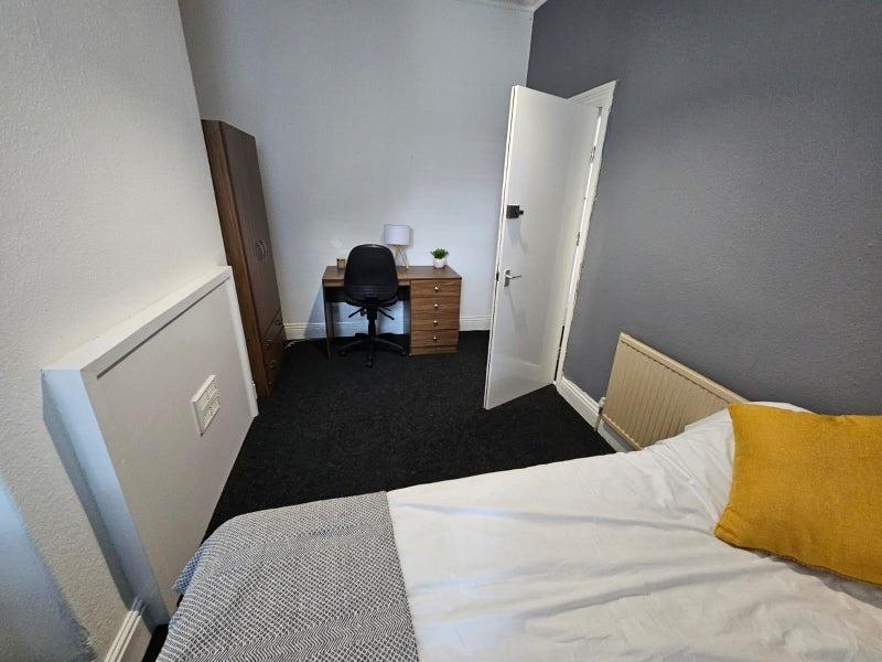 A cozy single bedroom featuring a comfortable b...
