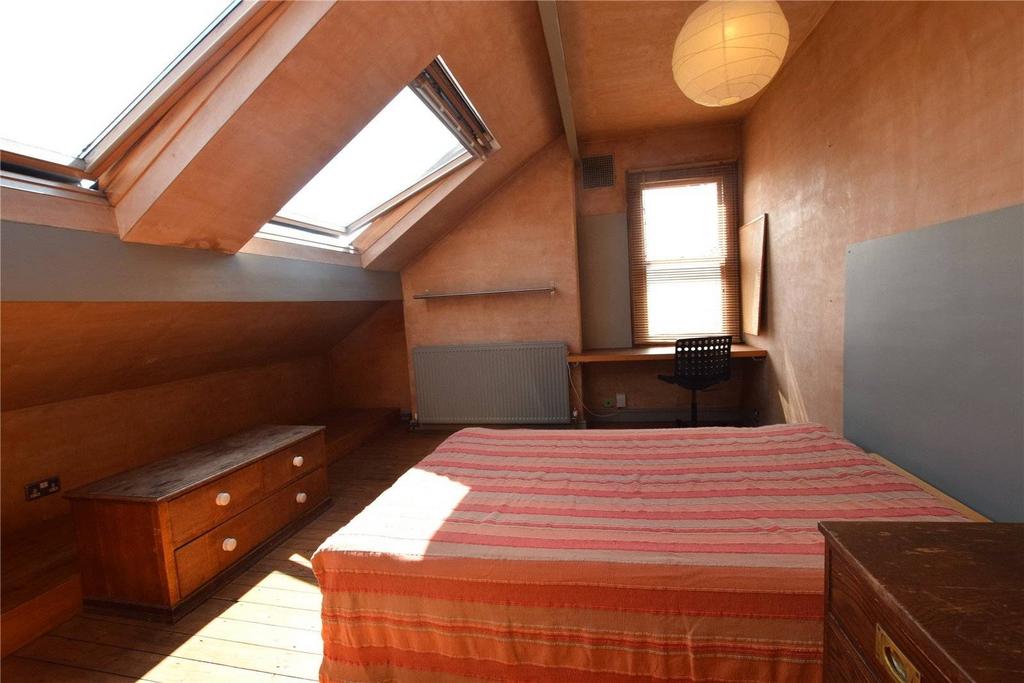 A cozy double bedroom featuring a slanted ceili...