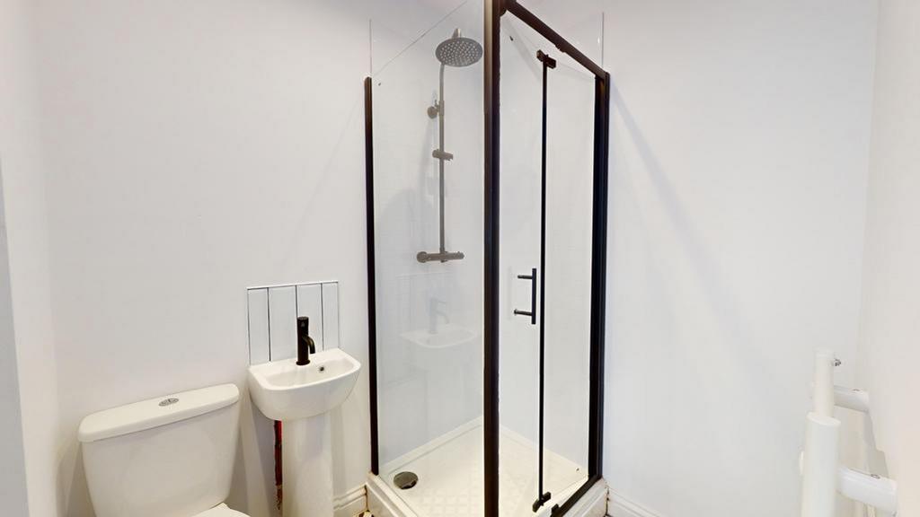 A modern bathroom featuring a spacious shower a...