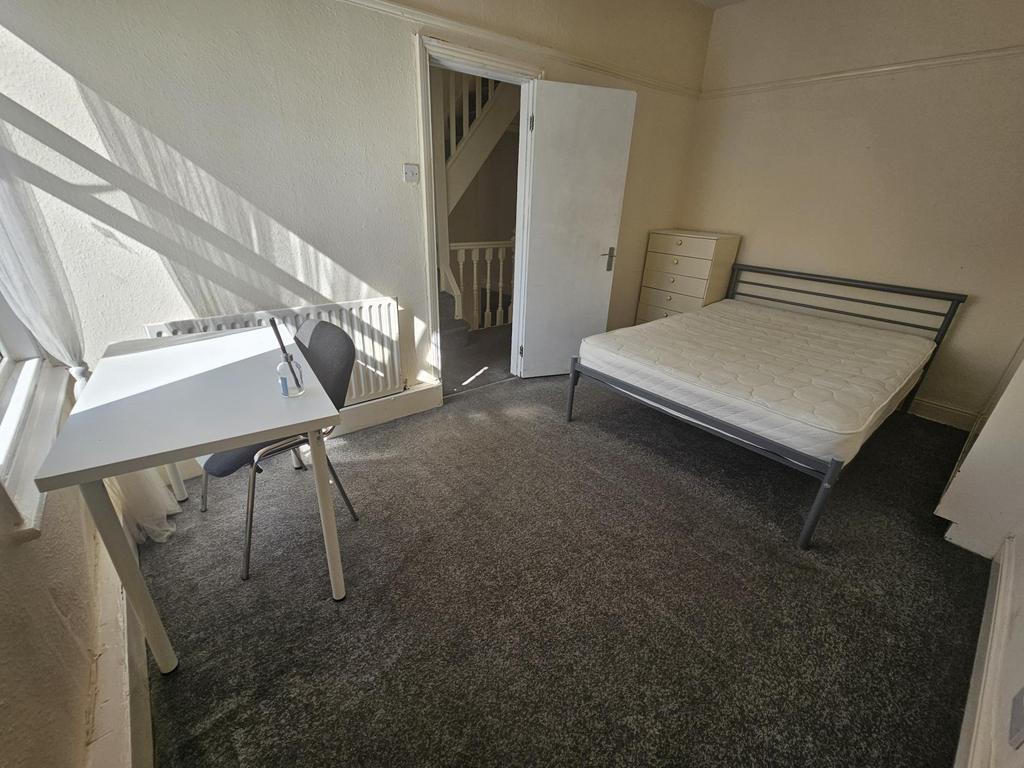 A modest, well-kept single bedroom with natural...