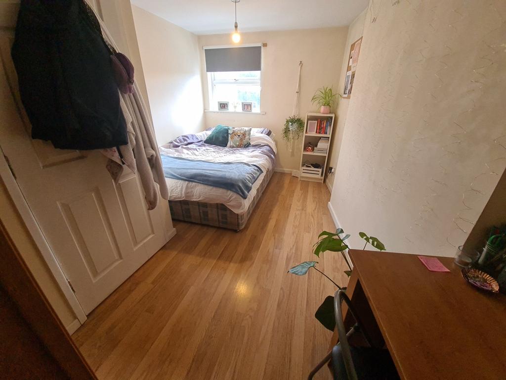A cozy single bedroom with a wooden floor, a be...