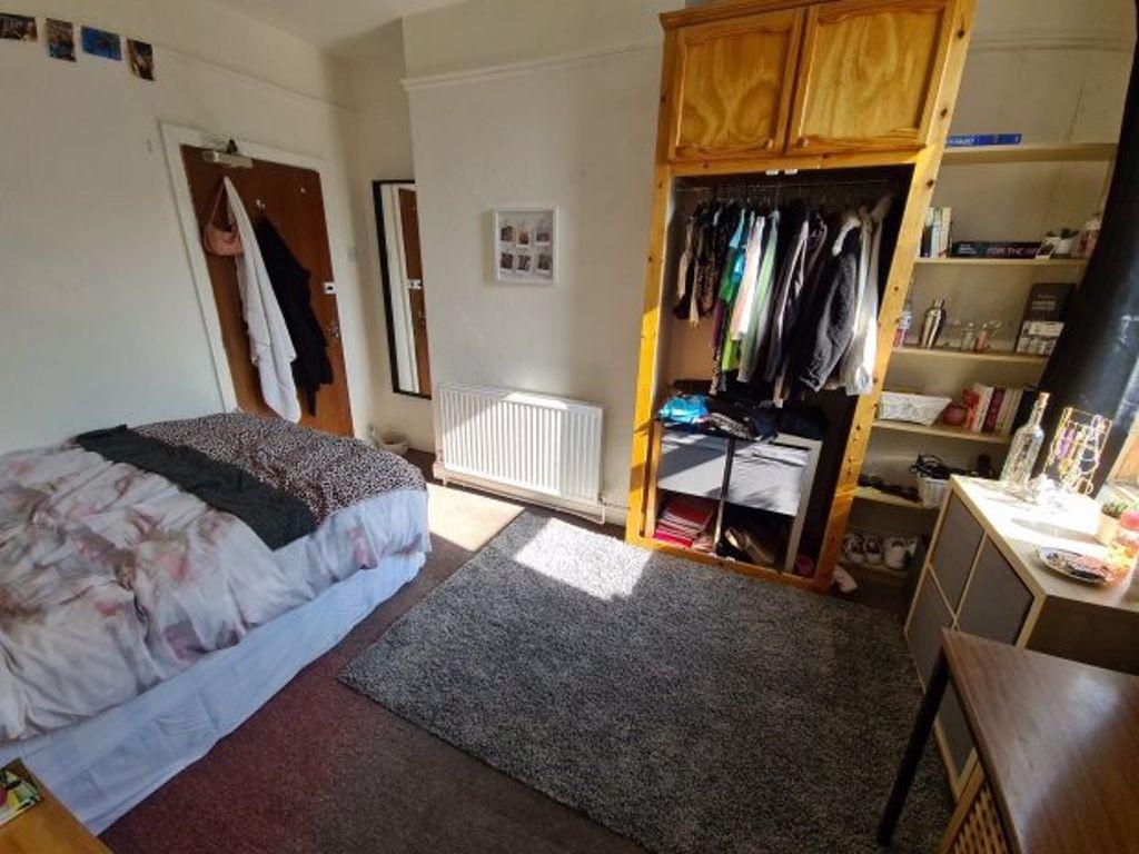 A cozy single bedroom with a bed, built-in wood...