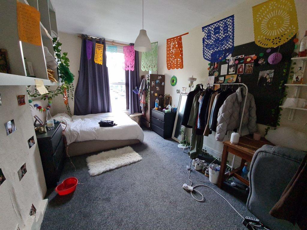 A cozy, well-lit single bedroom featuring a bed...