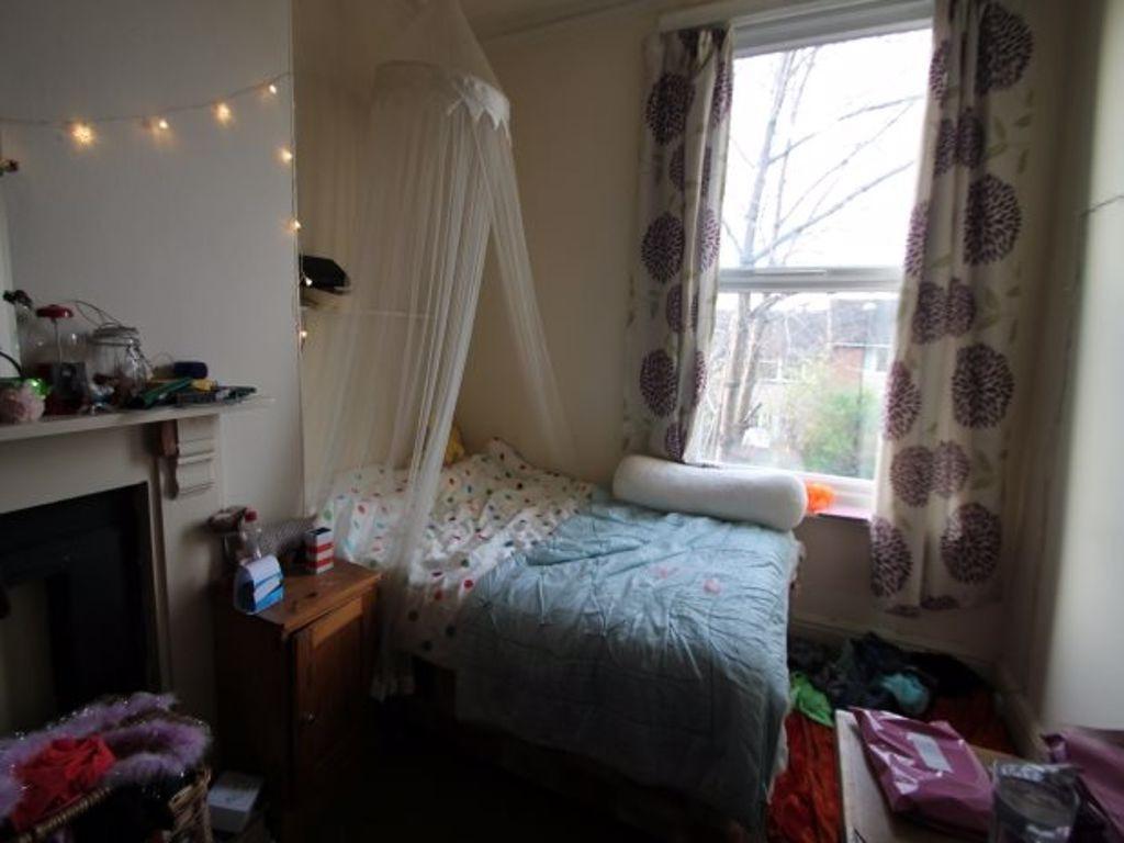 A cozy bedroom featuring a single bed with a pa...