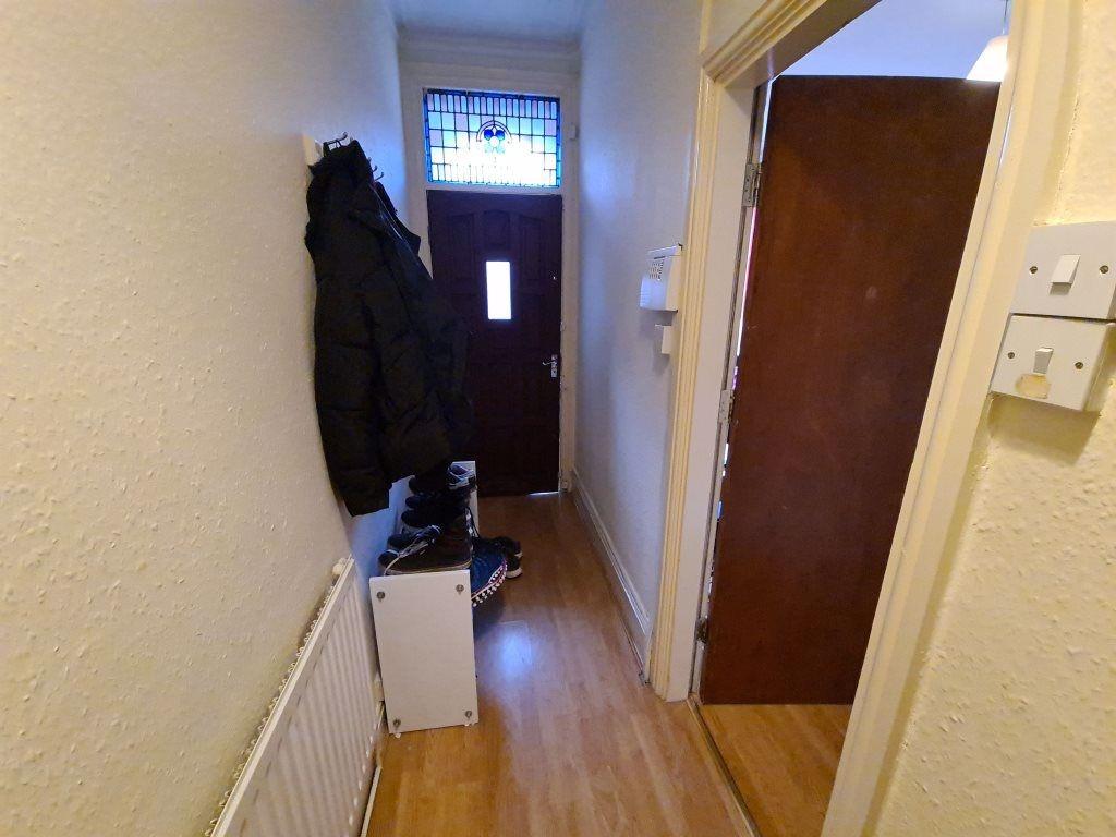 A narrow hallway featuring light wood flooring,...