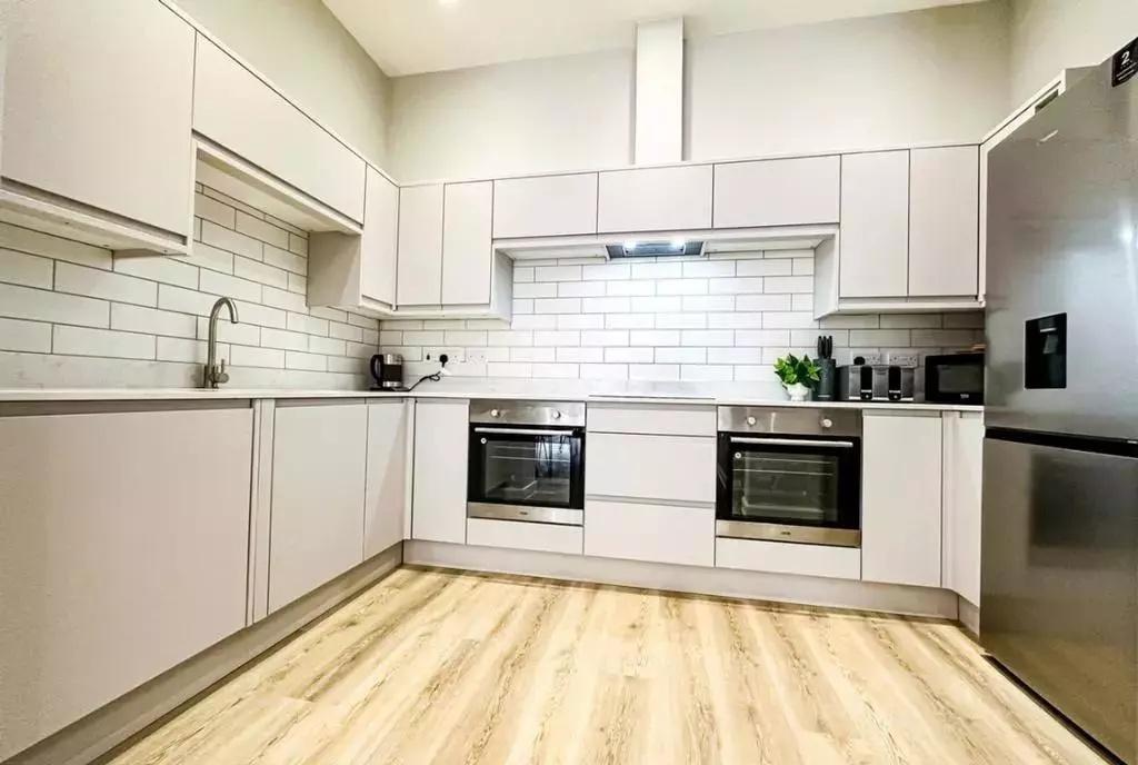 A modern, bright kitchen featuring sleek white ...