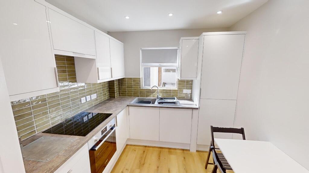 Bright and modern kitchen with white cabinetry,...