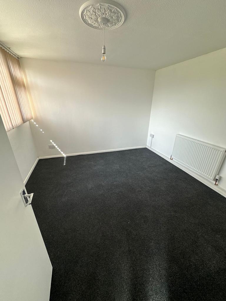 A clean and simple single bedroom with dark car...