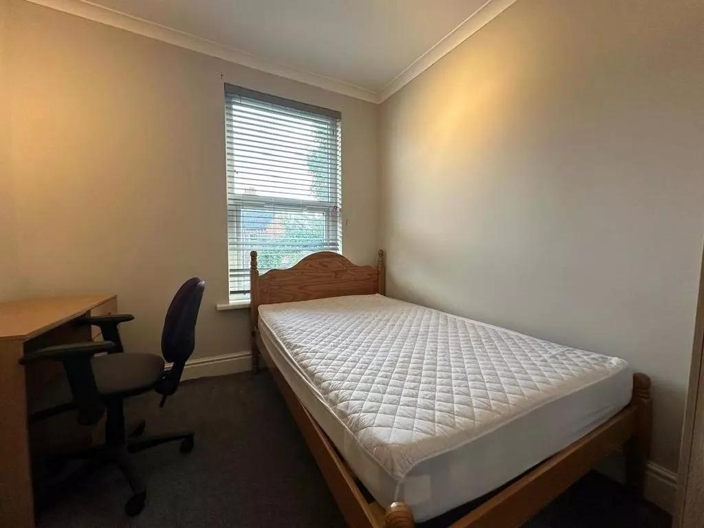 A cozy single bedroom featuring a wooden bed fr...